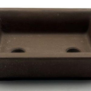 May include: A brown rectangular bonsai pot with two drainage holes. The pot has a slightly textured surface and a raised rim. The pot is designed for growing small trees and plants.
