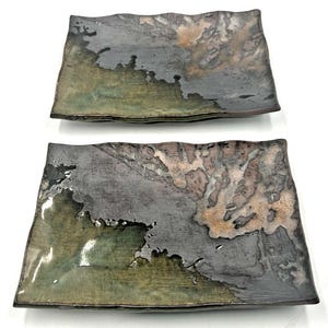 Pode incluir: Duas placas retangulares de cerâmica com um design texturizado único. As placas apresentam uma mistura de cores, incluindo cinza, verde e marrom, com um acabamento brilhante. As bordas têm uma forma ondulada e orgânica.