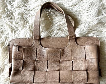 May include: A woven leather handbag with two top handles. The bag is a light brown color and has a woven pattern.