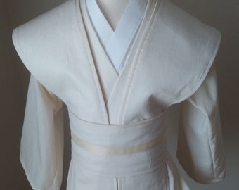 May include: A white robe with a long, flowing collar and a sash tied at the waist. The robe has long sleeves and a wide, flowing hem.