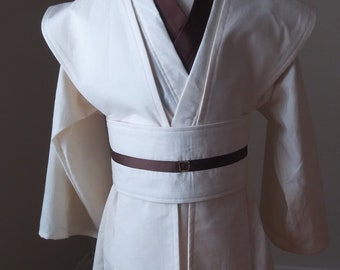 May include: A white robe with a brown sash and collar. The robe has long sleeves and a V-neck.