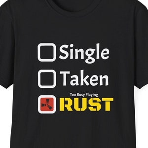 May include: Black t-shirt with a white graphic that says "Single, Taken, Too Busy Playing Rust" with a Rust logo.