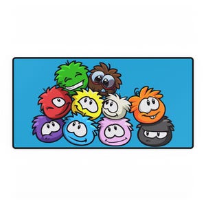 May include: A blue rectangular mat featuring a collection of cartoon characters with round, fluffy bodies and expressive faces. The characters are in various colors, including green, red, yellow, and purple, against a solid blue background.