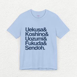 Puede incluir: Camiseta azul claro con una impresión azul marino de los nombres "Uekusa & Koshino & Uozumi & Fukuda & Sendoh."