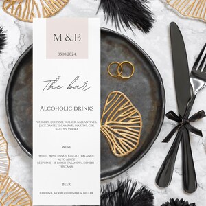 May include: A wedding menu card with black and gold accents. The card features the text "M&B" and "The bar" with a list of alcoholic drinks, including whiskey, wine, and beer.