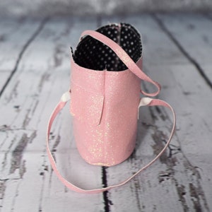 May include: A pink glitter tote bag with a black and white polka dot lining. The bag has a single strap.