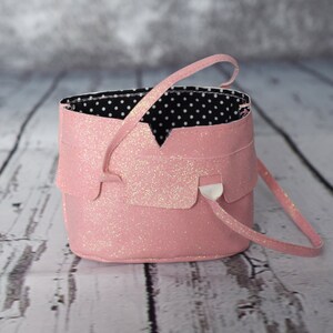 May include: A pink glitter handbag with a black and white polka dot lining. The bag has a single strap and a flap closure.