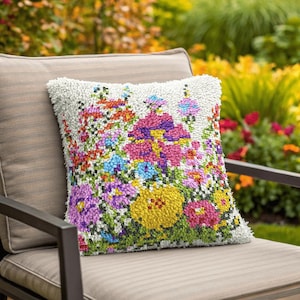 May include: A white cushion with a colourful floral design. The cushion features a variety of flowers in shades of pink, purple, yellow, and blue, with green leaves and stems. The cushion is made of a soft, plush material and would be a great addition to any home.