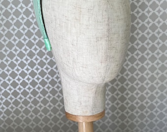 Bellissimo cerchietto con nodo e aureola color verde pallido. Perfetto per matrimoni, feste, corse o qualsiasi altro evento speciale.