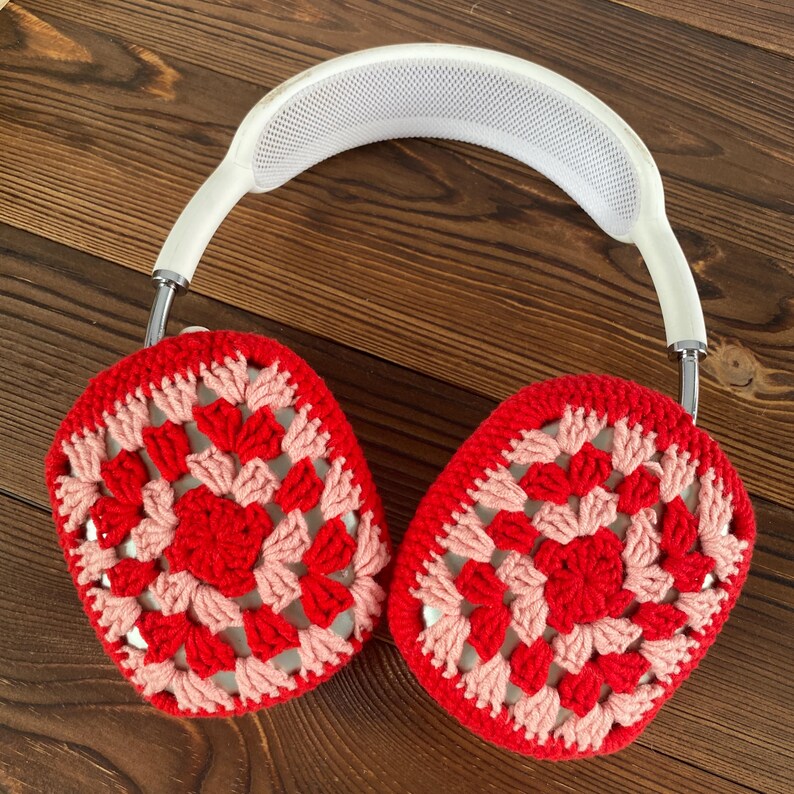 Op de afbeelding: Witte koptelefoon met rode en roze gehaakte oorkappen. De oorkappen zijn gemaakt met een granny square patroon.