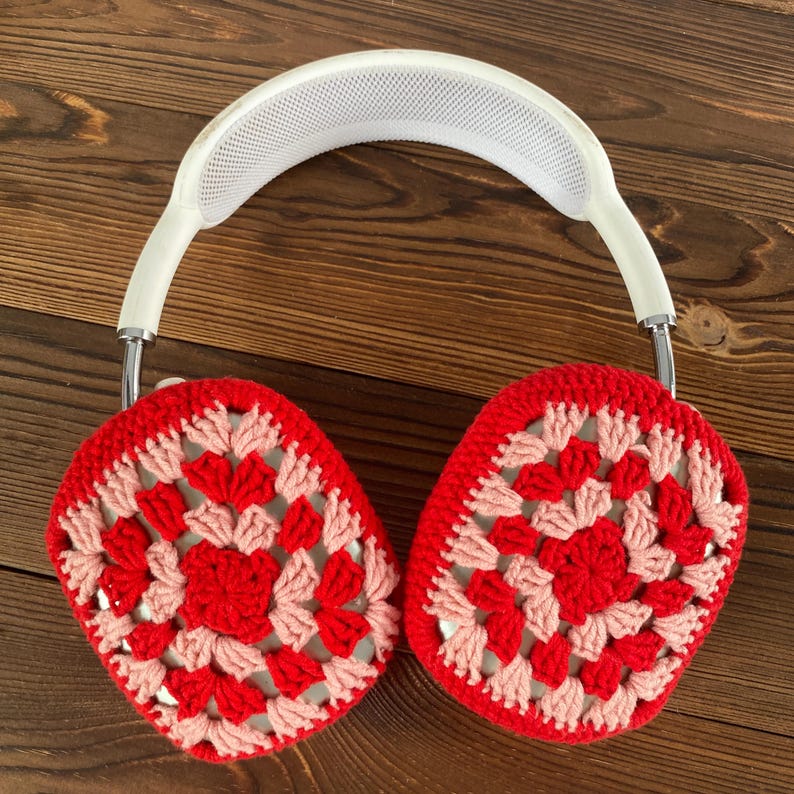 Op de afbeelding: Witte koptelefoon met rode en roze gebreide oorkappen. De oorkappen zijn gemaakt met een granny square patroon.