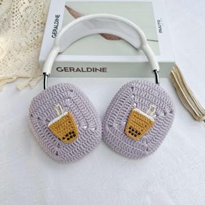 May include: Purple crocheted headphone covers with a brown and white embroidered boba tea design.