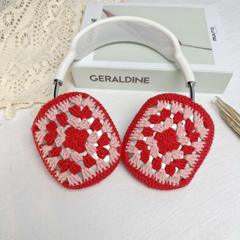 Op de afbeelding: Witte koptelefoon met rode en roze gehaakte oorkappen. De oorkappen hebben een granny square patroon.