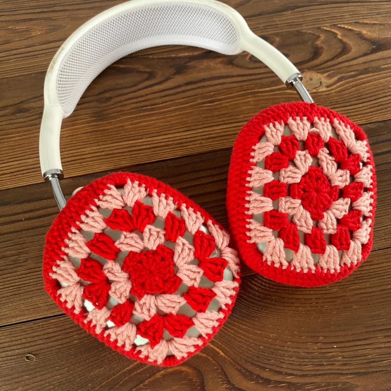 Op de afbeelding: Witte koptelefoon met rode en roze gehaakte oorkappen. De oorkappen zijn gemaakt met een granny square patroon.