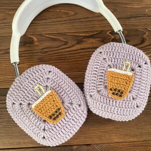 May include: Purple crocheted headphone covers with a brown and white crocheted boba tea design.