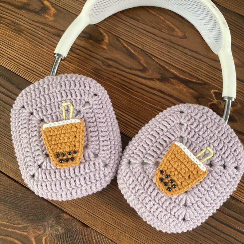 May include: Purple crocheted headphone covers with a brown and yellow crocheted boba tea design on each cover.