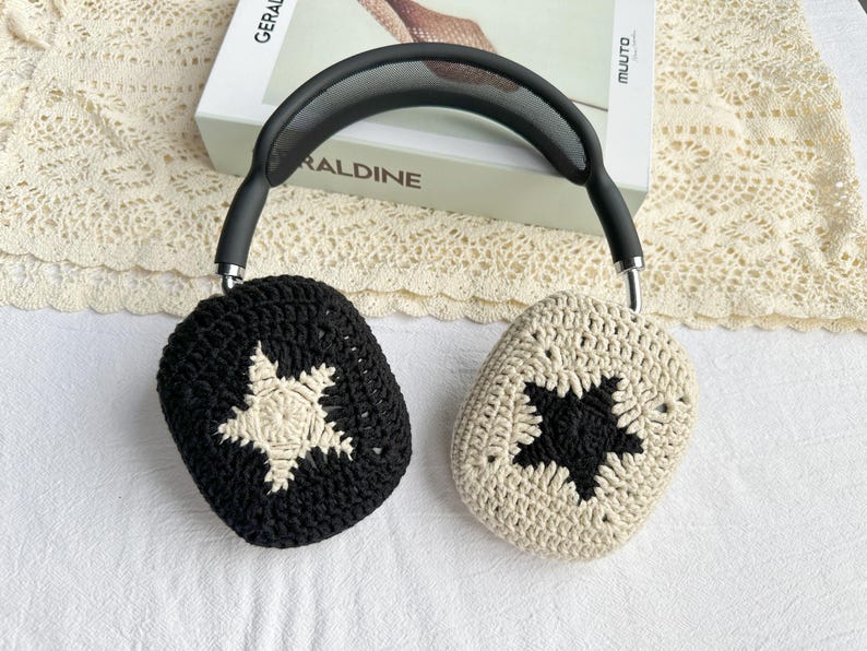 May include: Black and white crocheted headphone covers with a star design. The covers are made of a soft, textured yarn.