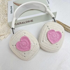 May include: White crocheted headphones with pink heart-shaped embellishments. The headphones have a white headband with a mesh design.
