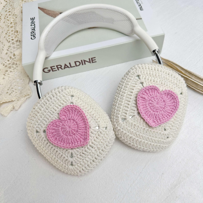 May include: White crocheted headphones with pink heart-shaped embellishments. The headphones have a white headband with a mesh design.