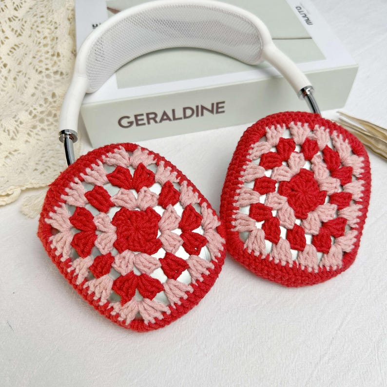 Op de afbeelding: Rode en roze gehaakte oorkappen met een witte hoofdband. De oorkappen zijn gemaakt met een granny square-patroon.