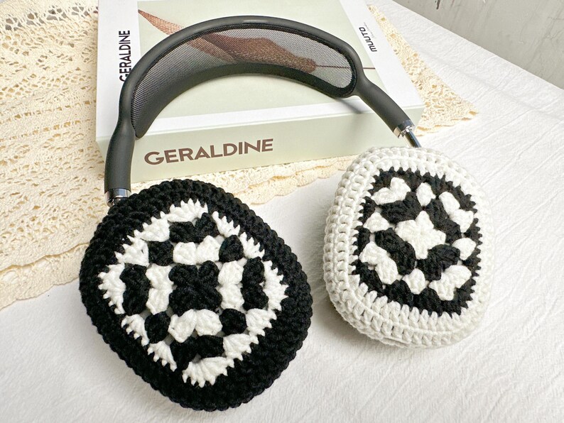 May include: Black and white crocheted earmuffs with a geometric pattern. The earmuffs are attached to a black headband.