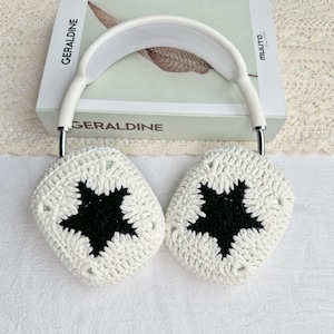 Puede incluir: Auriculares blancos con fundas de crochet con un dise&ntilde;o de estrella negra. Los auriculares descansan sobre un libro titulado "Geraldine". Las fundas son hechas a mano, agregando un toque art&iacute;stico &uacute;nico a los auriculares.