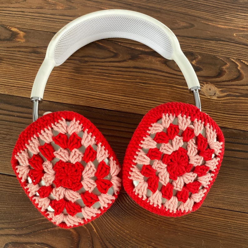 Op de afbeelding: Witte koptelefoon met rode en roze gehaakte oorkappen. De oorkappen hebben een granny square patroon.
