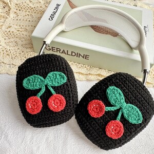 May include: Black crocheted headphone covers with a cherry design. The cherries are red with green leaves.