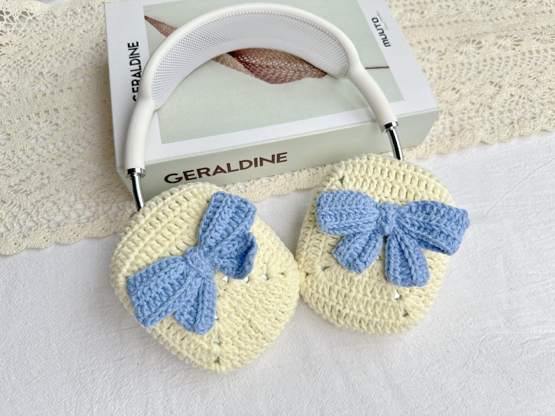 May include: A pair of crocheted ear warmers with blue bows. The ear warmers are cream coloured and the bows are a light blue.