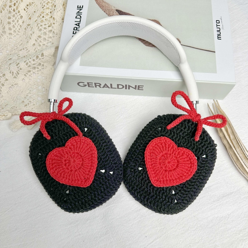 May include: Black crocheted headphone covers with red heart accents and white bows. The covers are attached to a white headband.