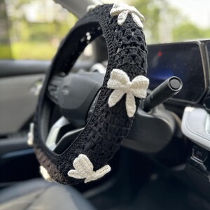 K&ouml;nnte beinhalten: Schwarze H&auml;kel-Lenkradabdeckung mit wei&szlig;en H&auml;kelblumen-Akzenten.