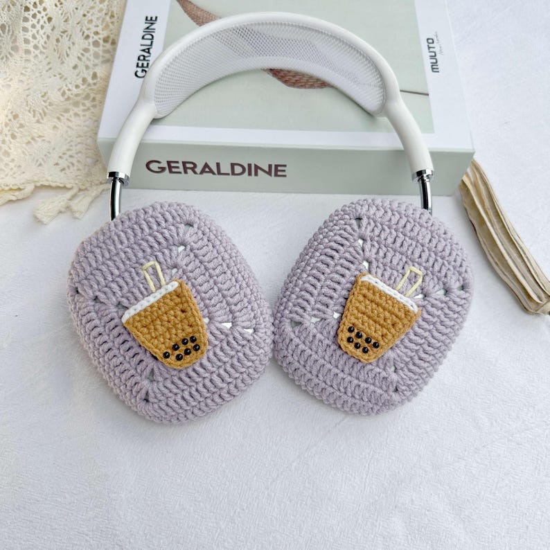 May include: Purple crocheted headphone covers with a brown and white embroidered boba tea design.