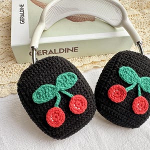 May include: Black knitted headphone covers with a cherry design. The cherries are red and green and are crocheted.