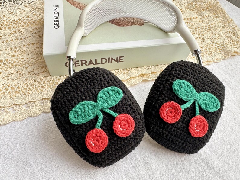 May include: Black knitted headphone covers with a cherry design. The cherries are red and green and are crocheted.
