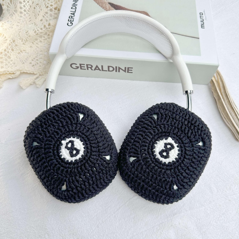 Puede incluir: Fundas para auriculares de crochet negro con un dise&ntilde;o de bola de billar blanca de 8. Las fundas est&aacute;n unidas a una diadema blanca.