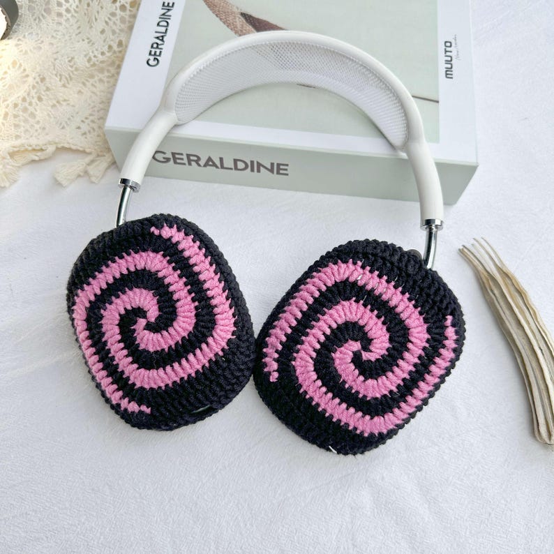 May include: White headband with black and pink crocheted earmuffs featuring a spiral pattern.