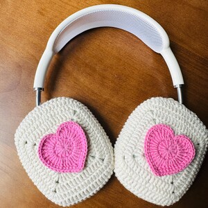 May include: White crocheted headphone covers with pink crocheted hearts on each earcup.