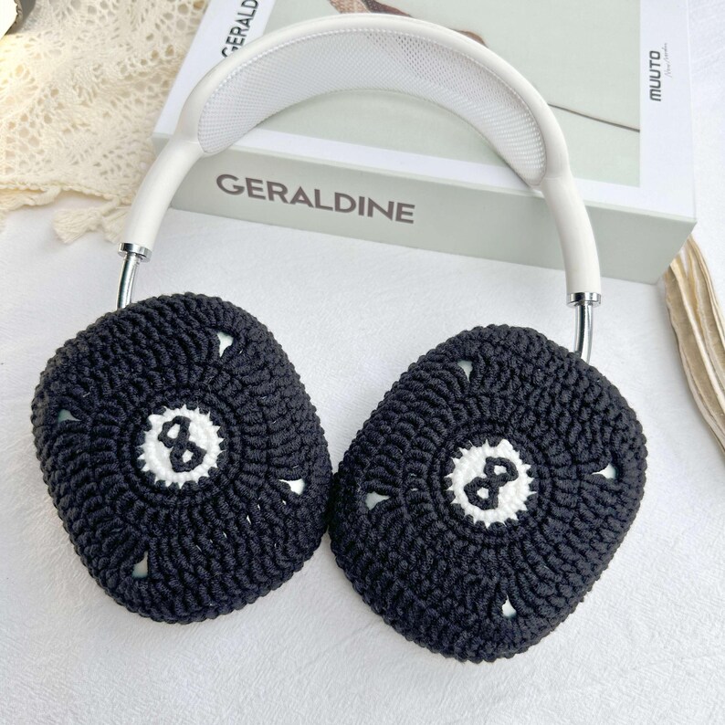Puede incluir: Auriculares blancos con cubiertas de orejas de crochet negro que presentan un dise&ntilde;o de bola 8 blanca. Las cubiertas de las orejas est&aacute;n hechas con un patr&oacute;n de crochet texturizado.