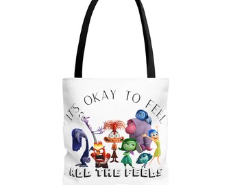 Könnte beinhalten: Weiße Einkaufstasche mit schwarzem Henkel. Die Tasche zeigt eine bunte Illustration von Figuren aus dem Film Inside Out, mit dem Text "Es ist okay, alle Gefühle zu fühlen".
