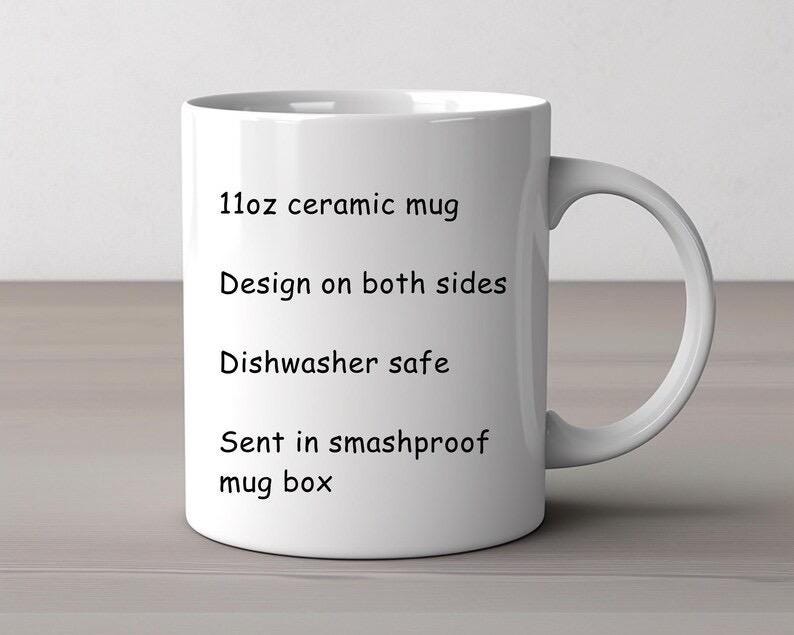 May include: A white ceramic mug with a curved handle. The mug is labeled as an 11oz mug with a design on both sides. The text also indicates the mug is dishwasher safe and sent in a smashproof mug box.