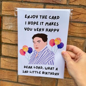 May include: A birthday card featuring a cartoon illustration of a person and balloons. The card's text reads: "ENJOY THE CARD I HOPE IT MAKES YOU VERY HAPPY DEAR LORD, WHAT A SAD LITTLE BIRTHDAY."