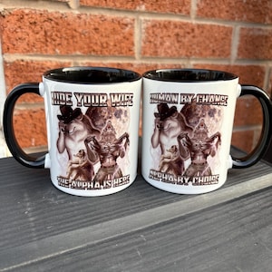 May include: Two white ceramic mugs with black handles and rims. Each mug features a graphic of a werewolf and the text "HIDE YOUR WIFE THE ALPHA IS HERE" and "HUMAN BY CHANCE ALPHA BY CHOICE".