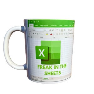 K&ouml;nnte beinhalten: Eine wei&szlig;e Keramiktasse mit einem gr&uuml;n-wei&szlig;en Microsoft Excel-Logo und dem Text "Freak in the Sheets".