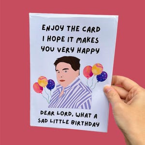 May include: A birthday card featuring a cartoon illustration of a man with balloons. The card's text reads: "ENJOY THE CARD I HOPE IT MAKES YOU VERY HAPPY DEAR LORD, WHAT A SAD LITTLE BIRTHDAY."
