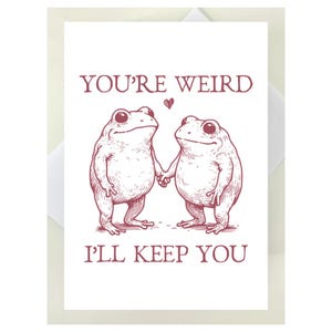 Puede incluir: Una tarjeta de felicitaci&oacute;n blanca con una ilustraci&oacute;n granate de dos ranas tomadas de la mano, con el texto "YOU'RE WEIRD, I'LL KEEP YOU". Un peque&ntilde;o coraz&oacute;n est&aacute; encima de las ranas. La tarjeta est&aacute; dentro de un sobre blanco.