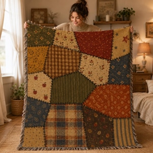 Puede incluir: Una manta tejida rectangular con un diseño de patchwork que incluye varios patrones de tela como cuadros, vichy, flores y motivos de manzanas en tonos rojo, verde, amarillo, azul y marrón, terminada con un borde de flecos en todos los lados.