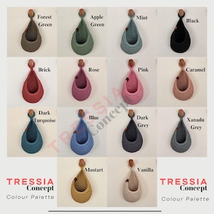 Puede incluir: Paleta de colores que muestra cestas colgantes de ganchillo en varios colores, incluyendo verde bosque, verde manzana, menta, negro, ladrillo, rosa, rosa, caramelo, turquesa oscuro, azul, gris oscuro, gris xanadu, mostaza y vainilla. Cada cesta est&aacute; suspendida por una clavija de madera.