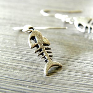 May include: Silver fish bone earrings with a hook closure. The earrings are small and delicate.