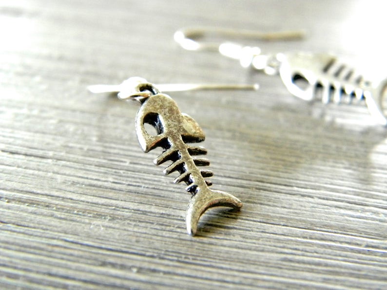 May include: Silver fish bone earrings with a hook closure. The earrings are small and delicate.