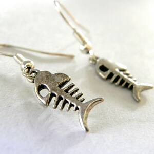 May include: A pair of silver fish bone earrings. The earrings are dangle style and feature a detailed fish bone design.